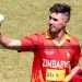 Cricketer holding up the ball in hand on the field during a cricket match