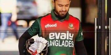 Cricket player walking while carrying a helmet